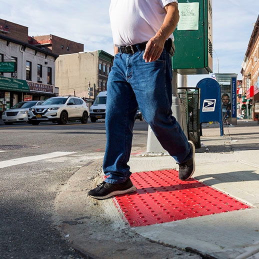 Pedestrian walking at crosswalk with ramp with red DWS