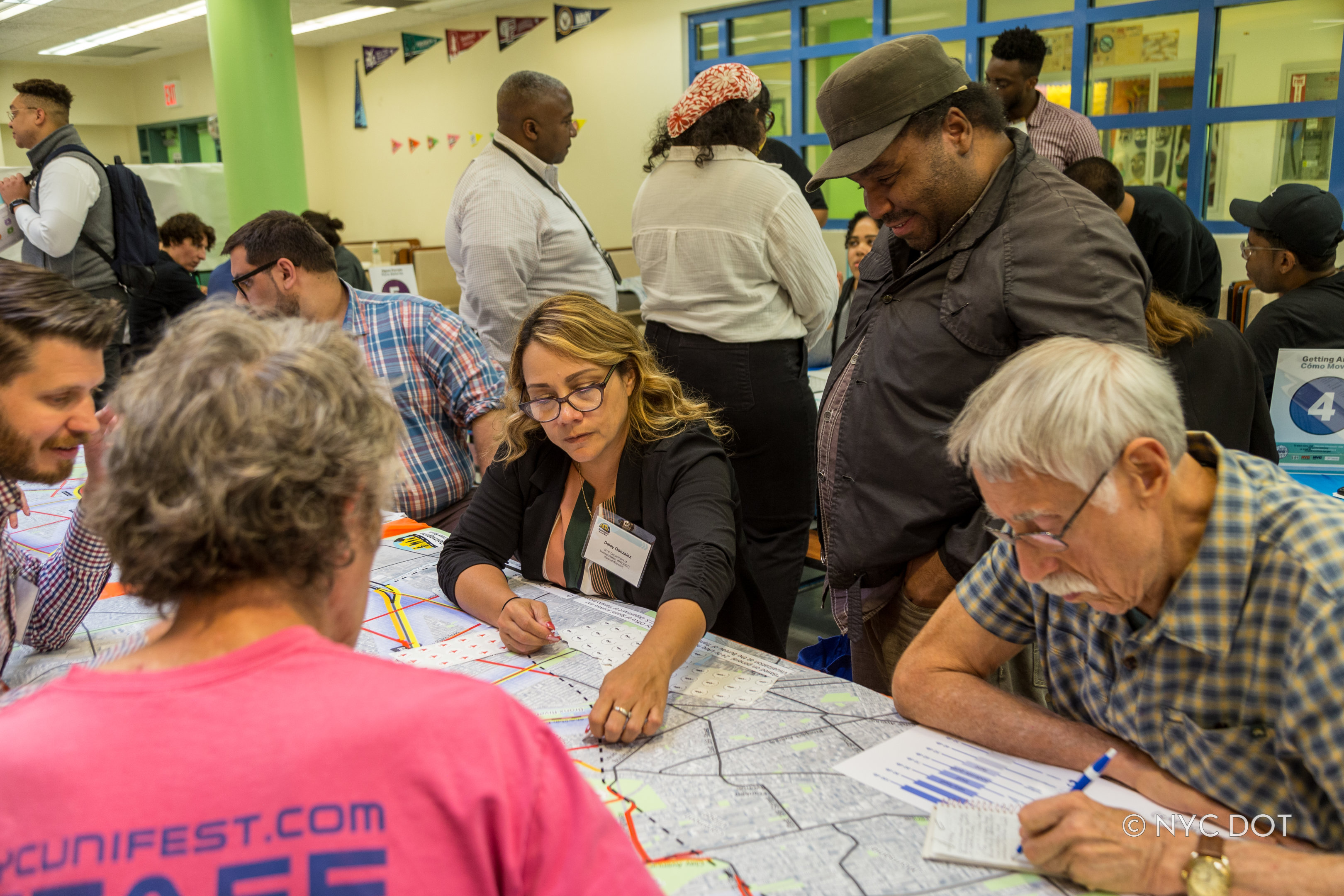 Community members and officials gather around a large map at a public open house event, discussing plans and providing feedback.